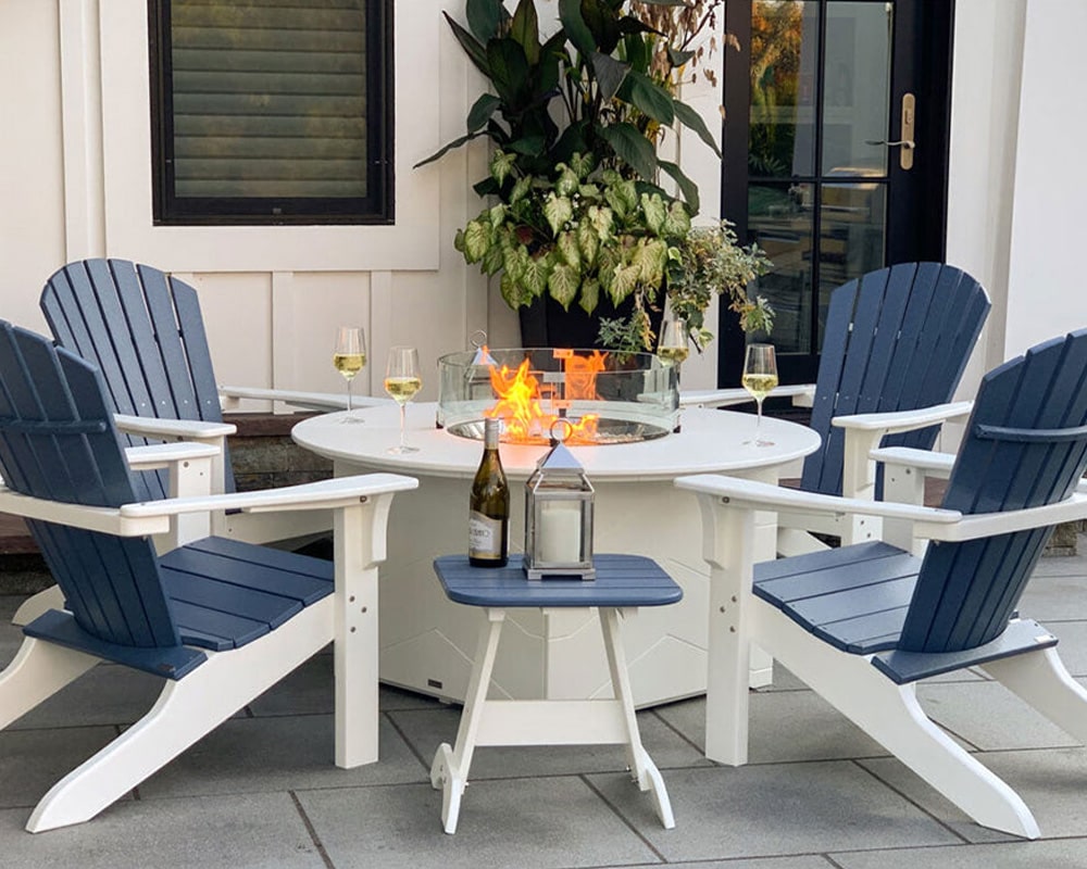 Cozy outdoor seating area with modern blue and white chairs around a fire table, wine served